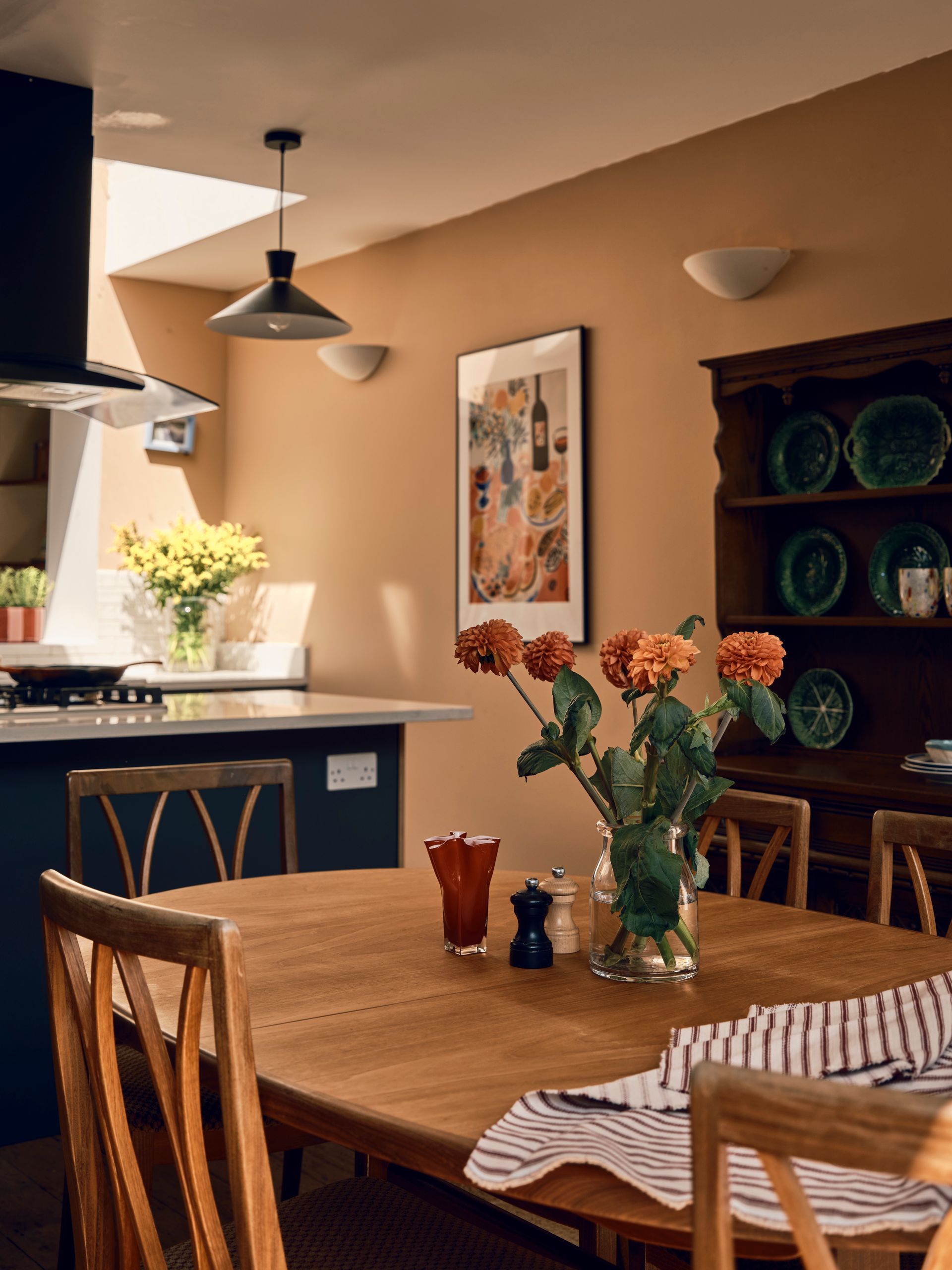 Dining area with an antique oak dresser, blue record cabinet and orange dahlias on a round wooden table