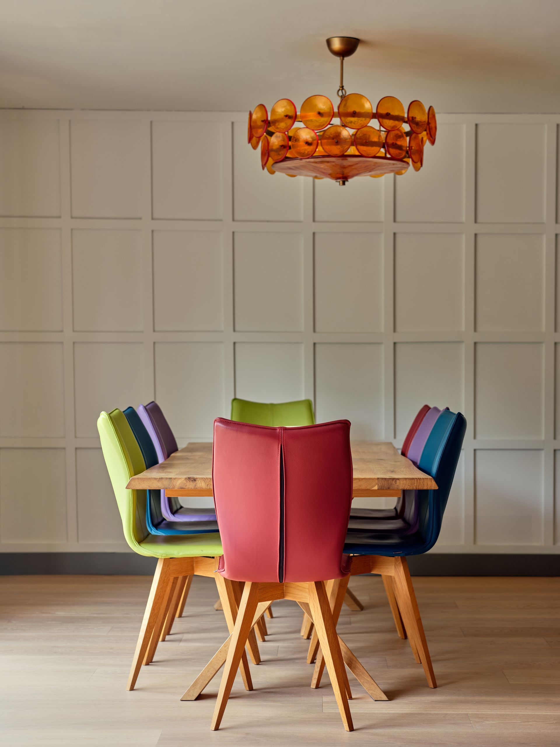Oak dining table with bespoke leather chairs in pink, green, blue and purple